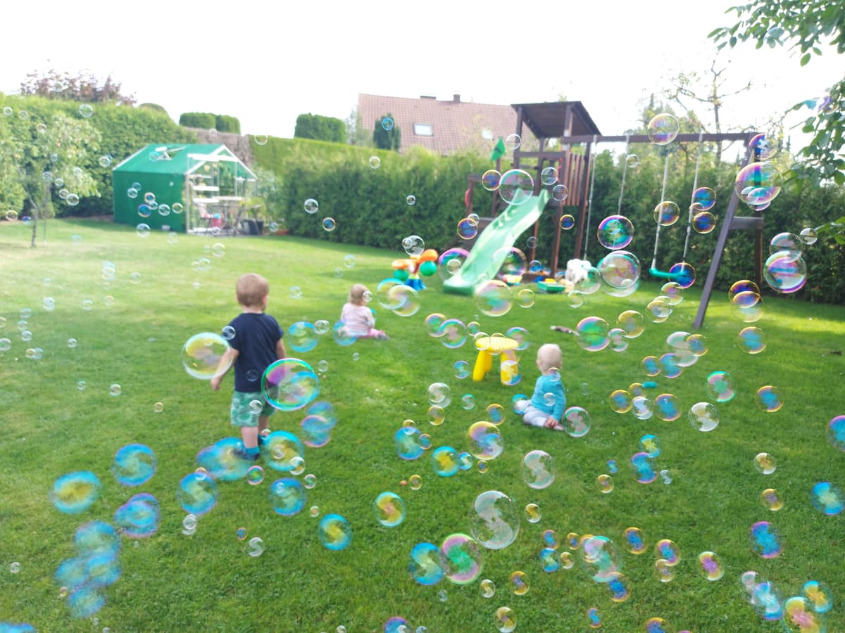Kinder spielen mit Seifenblasen im Garten